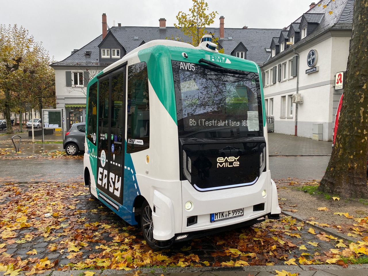 AV-Bus auf einem Parplatz mit Herbstlaub