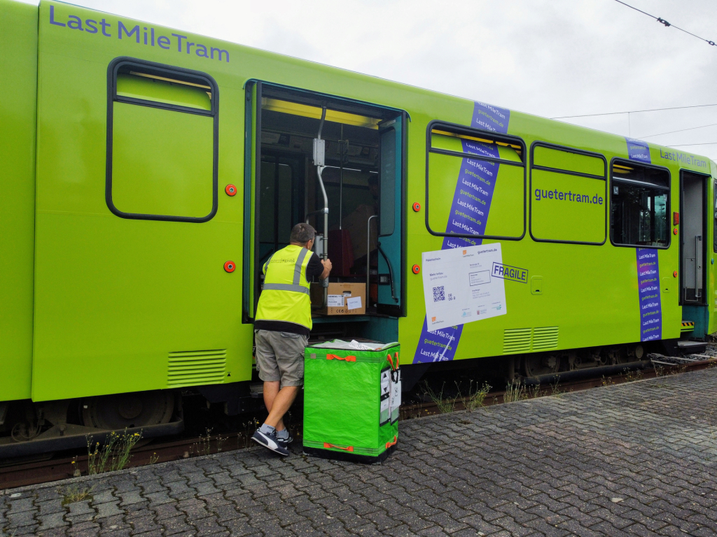 Pakete werden in die Gütertram, einen grün beklebten P-Wagen, geladen